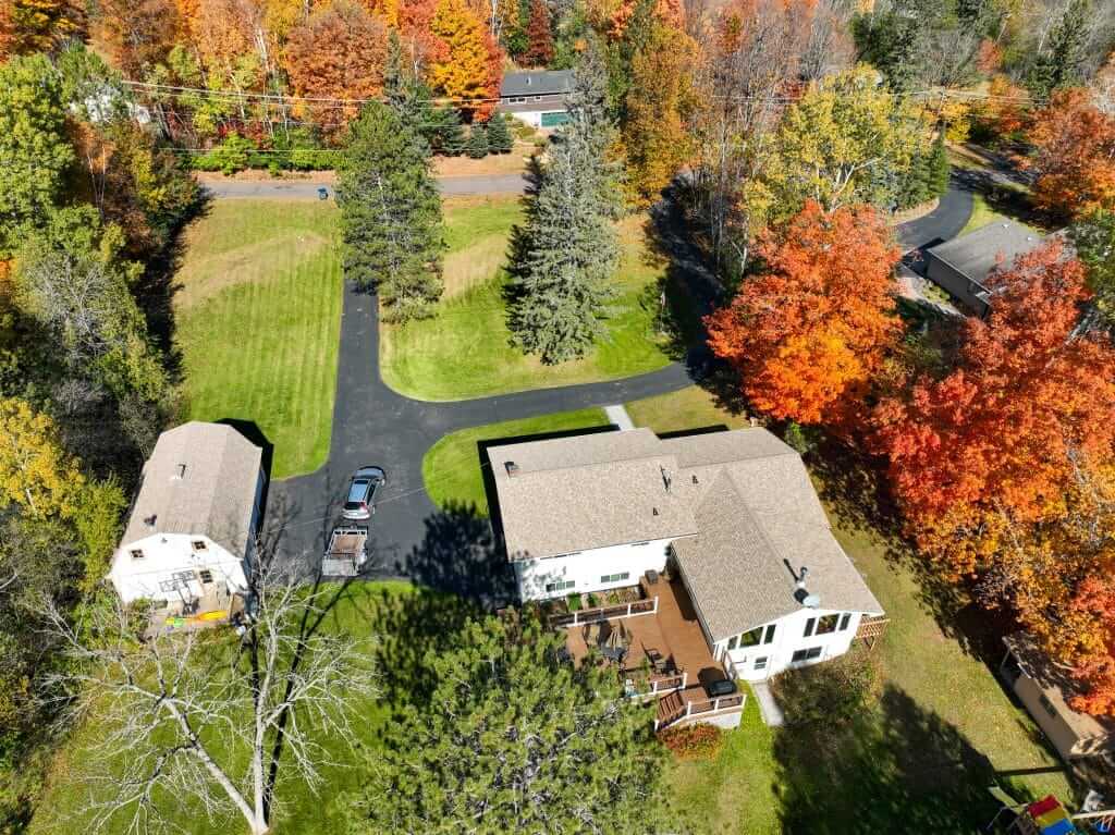 Aerial view of residential properties in Two Harbors, MN, showcasing autumn foliage, asphalt roofing, and well-maintained yards, highlighting the local environment relevant to Perrault Construction's roofing services.