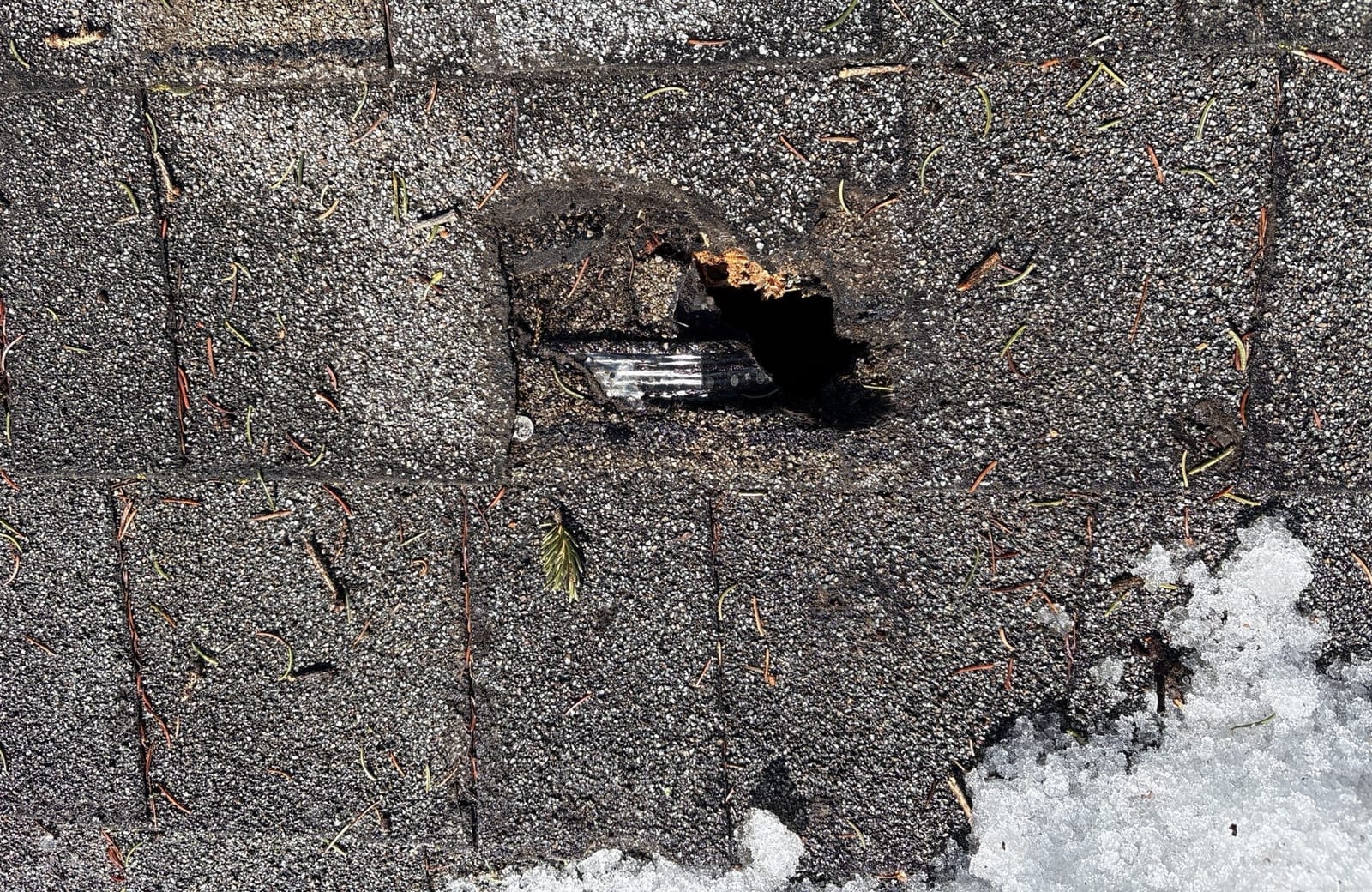 Shingle with a hole worn through it, before the work