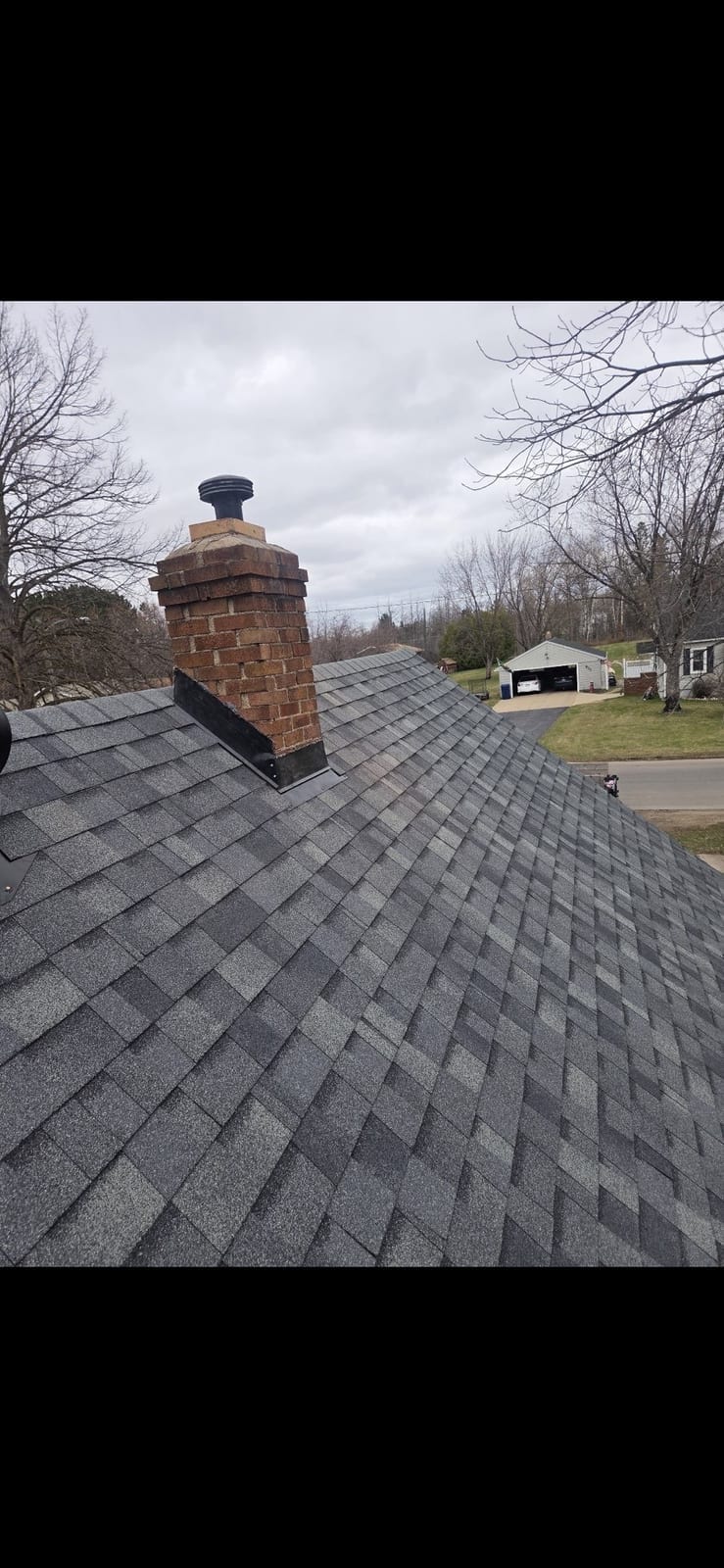 New shingles and black chimney flashing on the finished roof