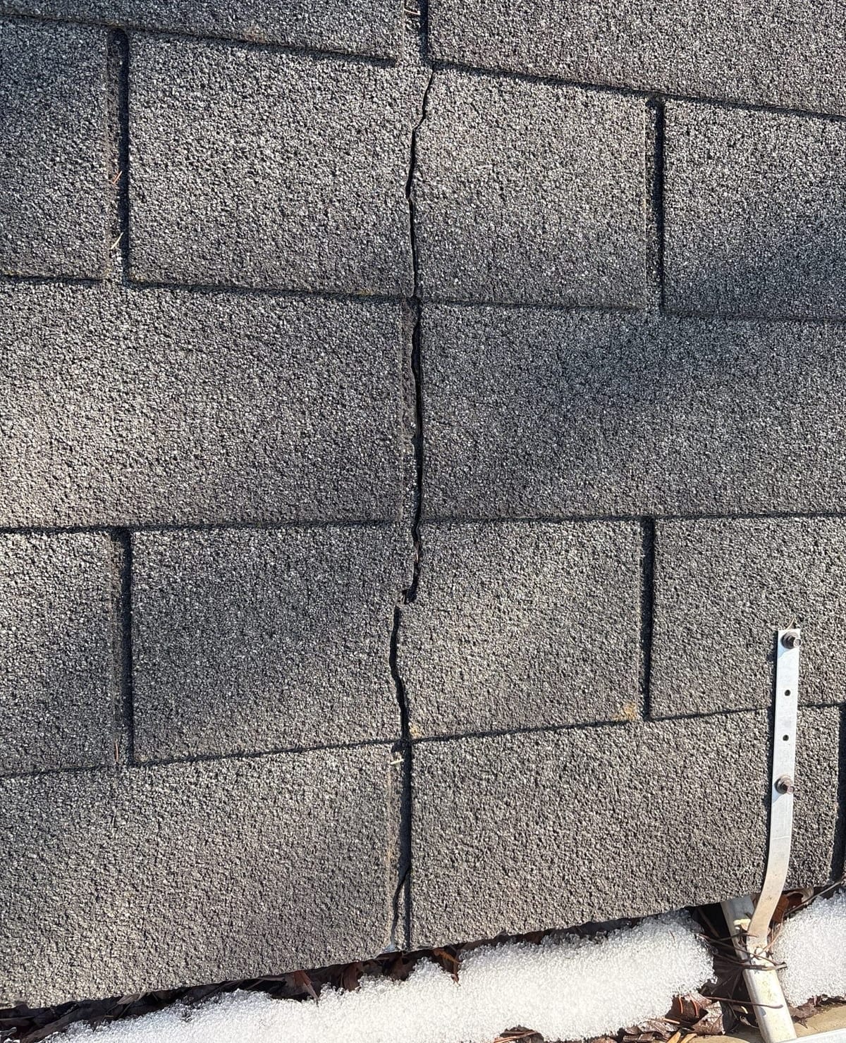 Cracked, brittle asphalt shingles on the old roof