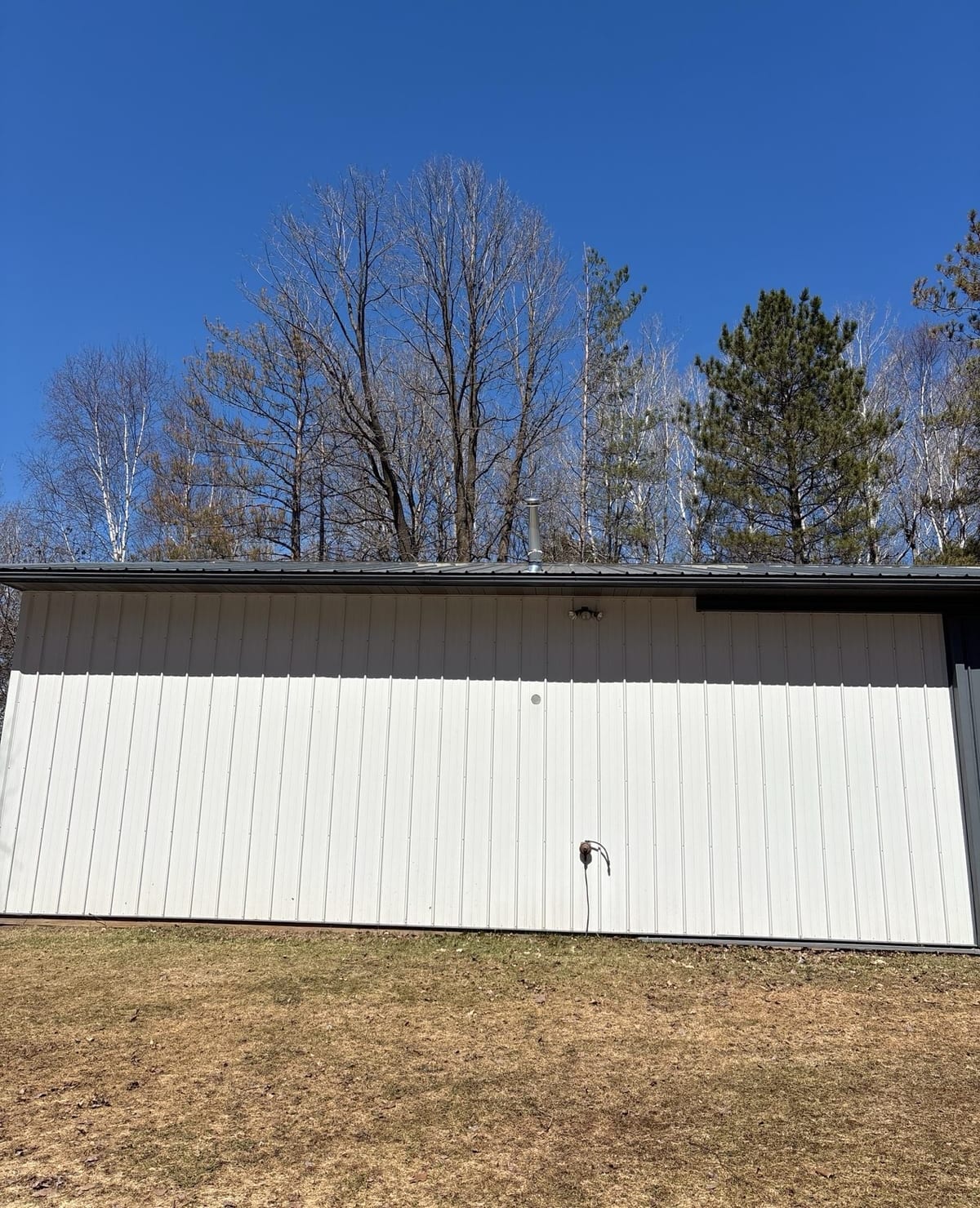 Outbuilding with a light metal roof seen from below against a clear sky