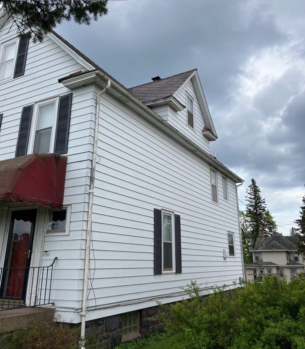 Old roof over a two-story home with dark shutters