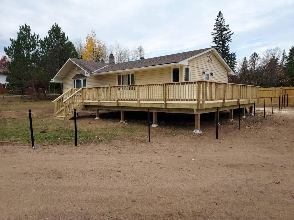 New wrap-around treated-lumber deck along the back of a single-story home